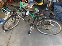 Full side view of black Mongoose Hill Topper mountain bike showing frame, tires, pedals and kickstand