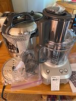 Breville slow cooker and Sous-Chef food processor on a wooden table with bubble wrapped parts and accessories in plastic bags.