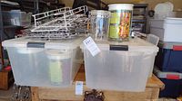 Photo showing two large translucent plastic storage totes with lids stacked side by side, metal wire hangers stacked on top of one tote, and two plastic canisters in front, one clear airtight with latch and one ClikClack with kiwi design and label.