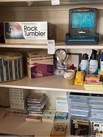 Photo of shelves with MSI Rock Tumbler box, PanaVue slide viewer box, and assorted office supplies and games