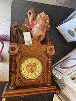 Full front view of a carved wooden wall clock with visible clock face and pendulum area.