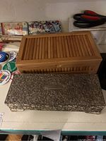 Photo showing two jewelry boxes, one wooden with slatted design and one ornate silver metal box on a table next to political pins.