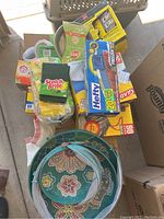 Overview of various household supply items including cleaning pads, freezer bags, storage bags, and paper towels on floor.