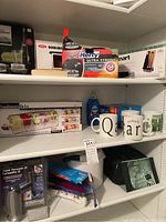 Shelves showing boxed plastic bags, mugs, and other kitchen items.