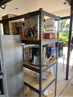 Metal shelving unit side view showing four wood composite shelves and gray metal frame.