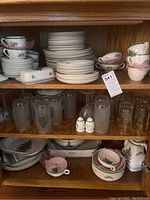 Top shelf showing stacked dinner and side plates with cups and saucers