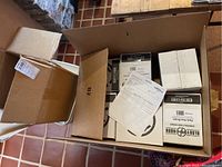 Top view of large cardboard box containing multiple smaller white boxes including Ready Hour Emergency Survivor Supplies and documents on top.