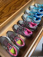 Four pairs of women's Asics sneakers lined up in a drawer, showing different color schemes and styles.