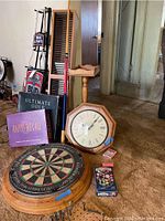 Photo of dartboard, board games, wall clock and CD rack showing lot contents