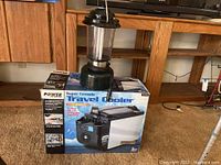 Full view of Coleman camping lantern placed on top of the boxed Super Console Travel Cooler.