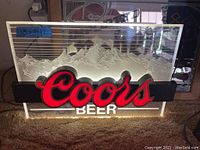 Illuminated Coors beer sign featuring red and white lettering and mountain design