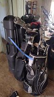 Two soft golf bags and black hard travel case strapped together