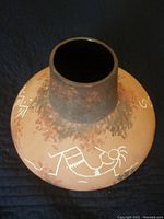 Top and side view of a round ceramic pottery vase with a narrow neck, decorated with a white Kokopelli figure and other traditional Native American designs on its rounded body.