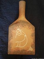 Front side of the rectangular ceramic pottery showing Kokopelli figure artwork with earthy mottled brown coloration.