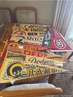 Full collection of nine vintage sports pennants laid out on a dining table.