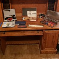 Wide view of all items arranged on wooden cabinet, including closed metal case, boxes, brush, and boxed tools