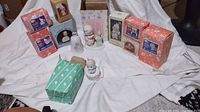 Group shot of Precious Moments figurines and original boxes arranged on white cloth