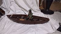 Side view of entire boat with fisherman and dog showing fishing pole and wooden boat structure.