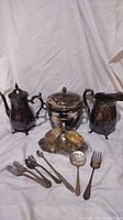 Vintage silver 800 marked teapot, sugar bowl, creamer, salt and pepper shakers, and assorted Hallmark flatware items arranged on white cloth background.