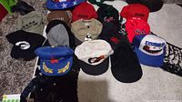 Overview of 17 assorted hats on carpet showing various colors and logos including a red, white, and blue star-spangled Uncle Sam leisure hat on the right.