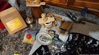 Overview of lot items on carpet including wooden figures, flask, flashlight, tray, shaving mug and other small items.