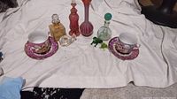 Full view of the lot including teacups and saucers, perfume bottles, and glass figurines on white backdrop