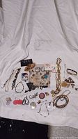 Full view of assorted costume and sterling jewelry items spread on fabric showing variety of types and styles