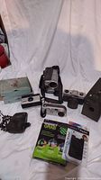 Overview photo showing all items in the lot including vintage cameras, radar detector, camera case, and phone accessories.