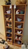Wooden shelves with multiple chicken figurines in various colors and designs arranged on shelves.