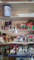 Wide view of shelves with assorted Christmas ornaments including tins, snowman decorations, tree displays, and other holiday decor