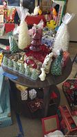 Photo of table with large cone-shaped tree candles in green, white, and red, red glass tree decoration, small green ceramic tree figurines, and ceramic Santa and snowman figurines.