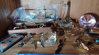 Overview of assorted costume jewelry including necklaces, pins, earrings, and a glass swan ring holder with crystal ball base.