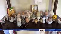 Shelf display of 20 decorative eggs paired with egg cups and stands in different materials and styles