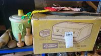 Vintage Lustroware bread box in original box alongside other kitchen items on a shelf