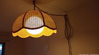 Photo of the wicker or rattan swag hanging lamp suspended by metal chain, showing texture and shape of lampshade