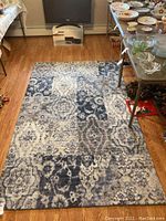 Top-down view of area rug with visible pattern and texture spread on hardwood floor underneath table and chairs.