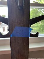 Close-up photo of the coat rack showing several wooden hooks attached to a central wooden post with a blue tape label marked '66'
