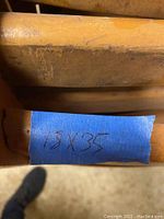 Close-up of blue tape label showing dimensions 18x35 inches on the wooden chair part.
