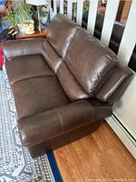 Brown leather-like loveseat showing overall seating and arm design.