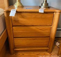 Front view of the oak nightstand chest of drawers showing its three drawers and wooden handles.