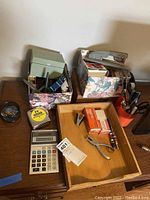 Photo of two floral box organizers on a wooden surface next to a vintage calculator, tape measure, stapler, hole puncher, and pencil in a wooden tray