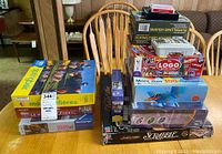 Overview of puzzles, games, and card decks stacked on a wooden table with chairs in background.