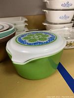 Opaque green Pyrex bowl with green floral lid, visible front and side profile