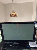 Full view of Samsung 48-inch plasma TV with remote control in front, showing screen and stand.