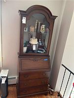 Full front view of the secretary desk showing glass door, shelves, writing area closed, and three lower drawers.