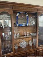 Full display cabinet showing stained glass art, Waterford candle sticks, and various glassware items including bowls and decanters.
