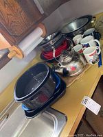 Overview photo of kitchen items on counter including bowls, mugs, tea kettle, and bakeware