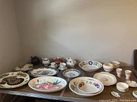 Wide shot of ceramic platters with teapots, teacups, bowls arranged on a table