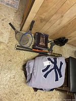 Overview photo of all items including weights, bats, binoculars, books, rackets, and folded blankets with Yankees logo