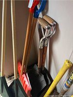 Photo showing wooden handle shovels with metal square and D-grip heads along with red and blue plastic snow shovels.